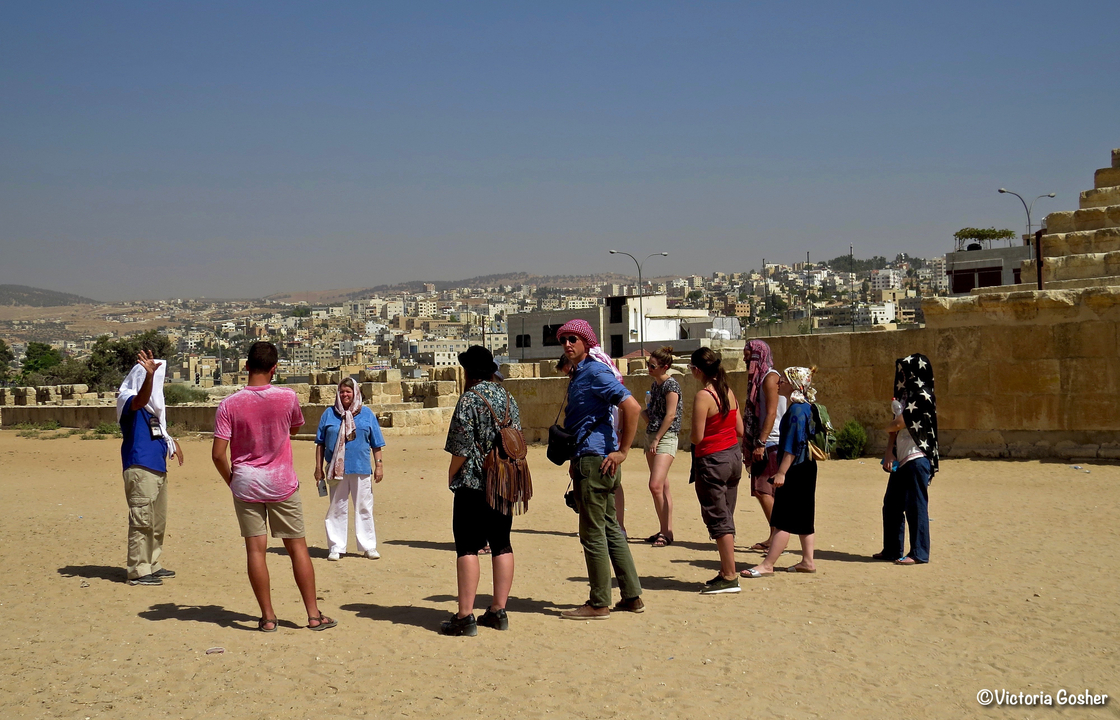 Groupe de personnes visitant un site archéologique dans un environnement désertique.