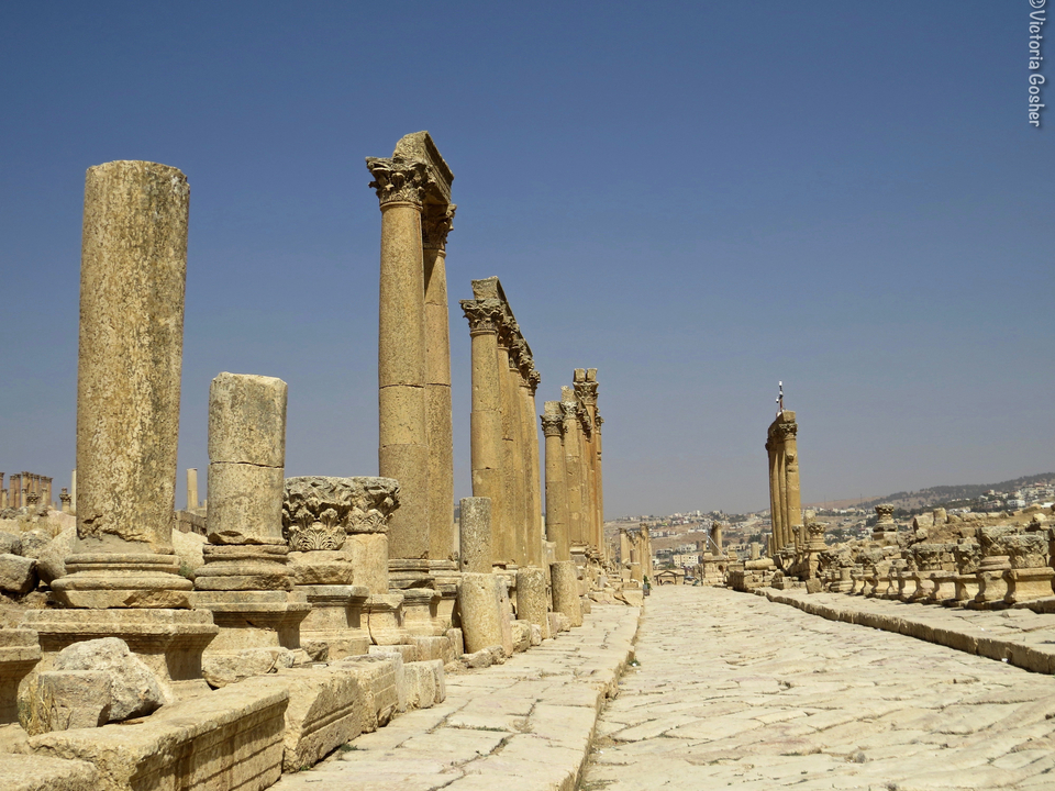 Alignement d'anciennes colonnes de pierre sous un ciel bleu clair.