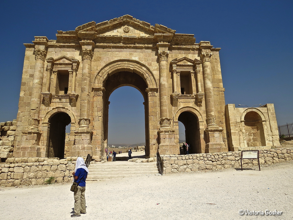 Ancienne arche architecturale avec des sculptures complexes et un ciel bleu.