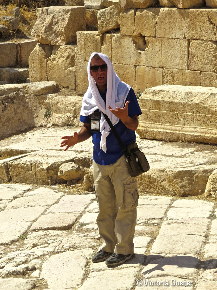 Guide touristique parlant dans un site archéologique avec des pierres anciennes.