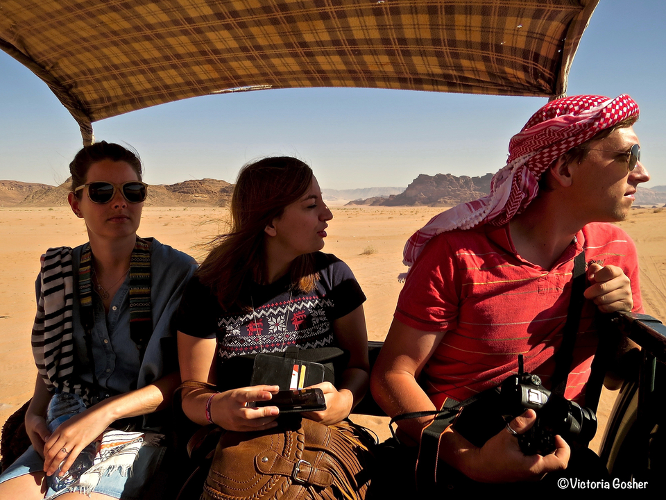 Personnes assises dans un véhicule à toit ouvert dans le désert.