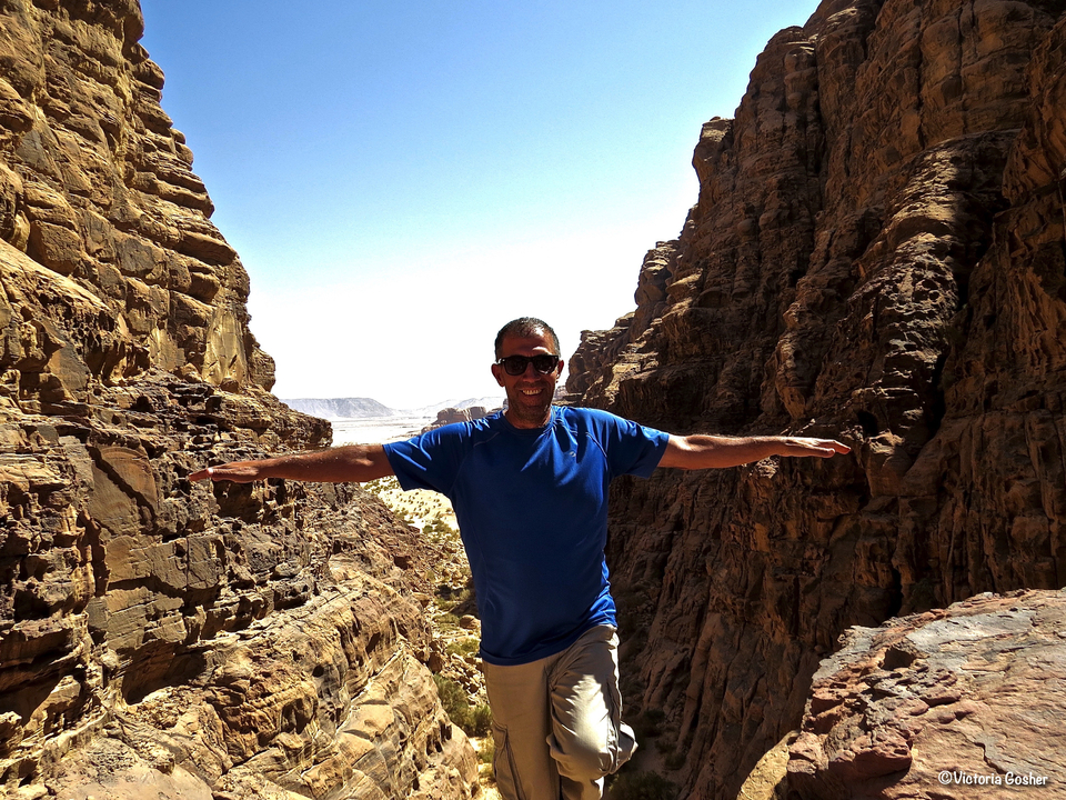 Homme souriant avec les bras tendus dans un canyon.