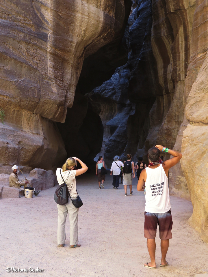 Tourists approaching a cave entrance within rock formations.