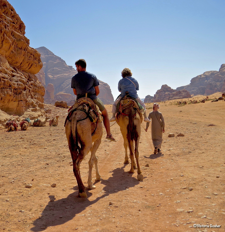 Des personnes à dos de chameau dans un paysage désertique.
