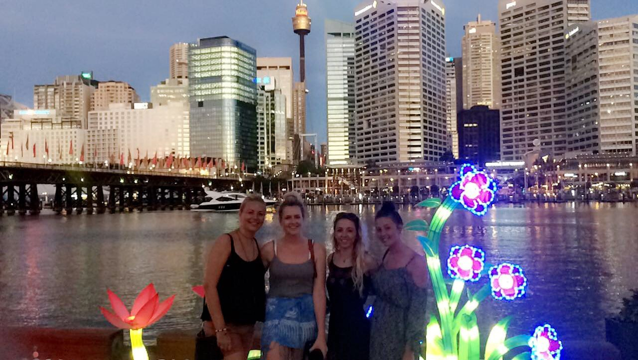 People posing at a waterfront cityscape at dusk