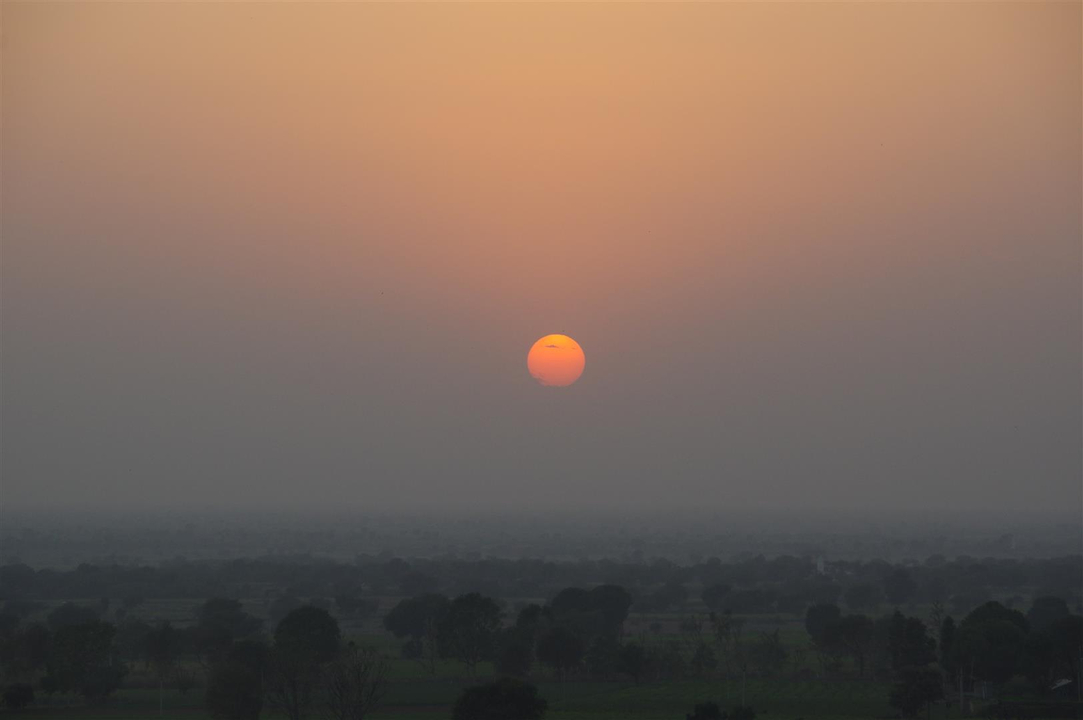 Coucher de soleil sur un paysage avec des arbres visibles.