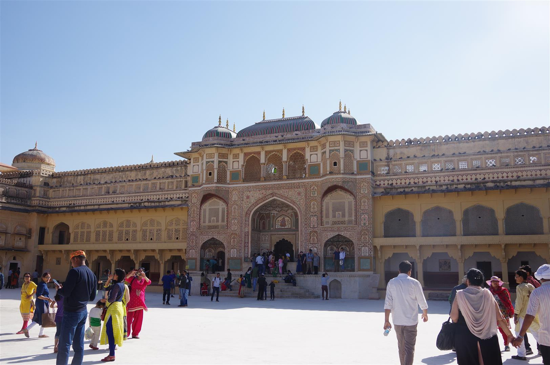 Une grande cour de palais avec des gens qui se promènent.