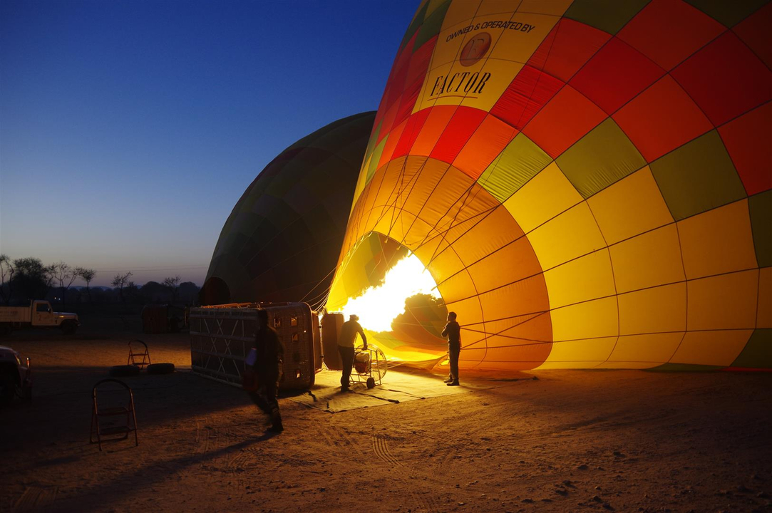 Personnes préparant une montgolfière pour un vol à l'aube.