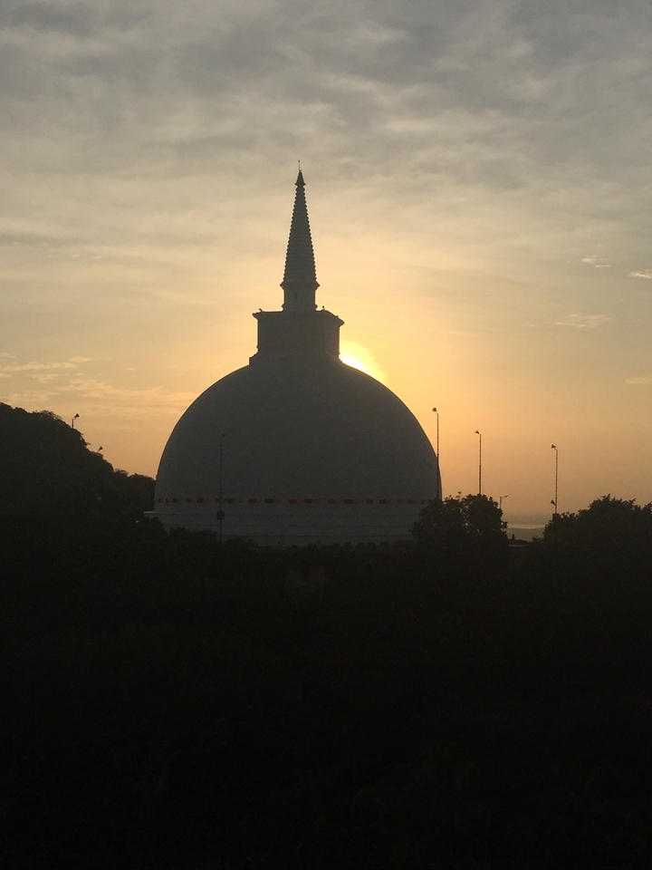 Silhouette d'un stupa avec le soleil se couchant derrière lui.