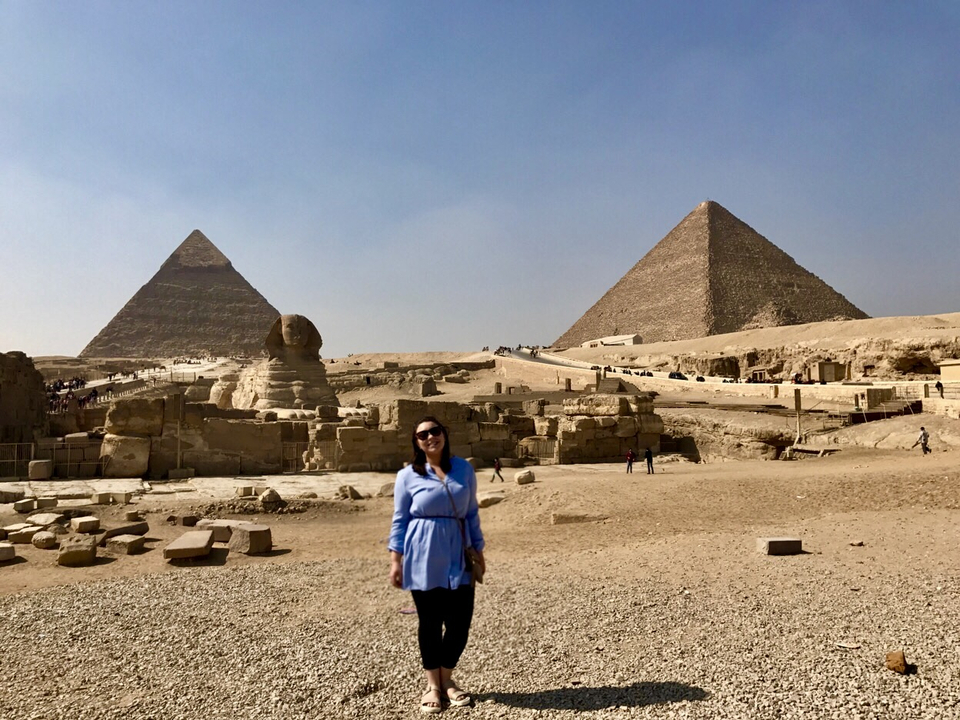 Person standing before the Pyramids and the Sphinx.