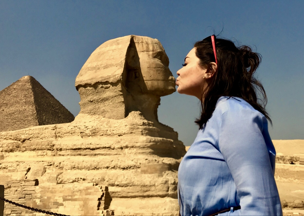 Person playfully interacting with the Sphinx in Egypt.