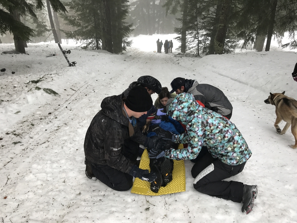Groupe de personnes s'occupant de quelqu'un sur un chemin enneigé