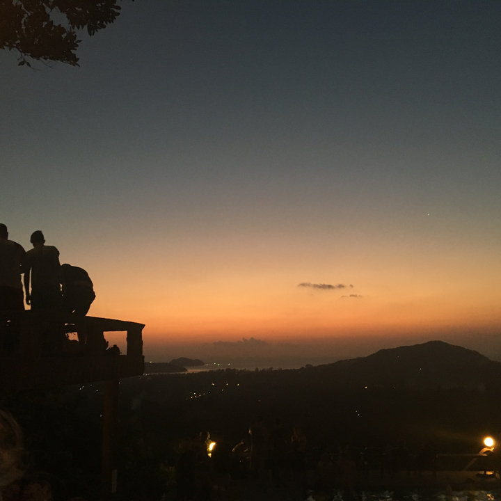 Silhouettes of people against a sunset over water.