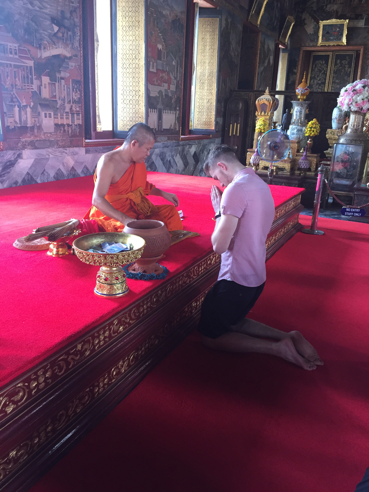Monk with visitor in a temple engaged in a ritual.