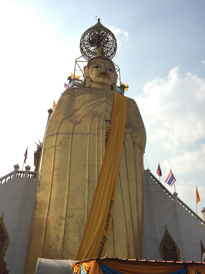 Tall golden Buddha statue wrapped with a yellow cloth.