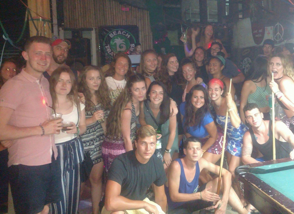 Group of people gathered in a lively setting playing pool.