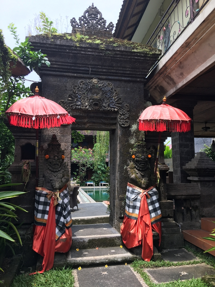 Une entrée de temple décorée avec deux statues et des parapluies rouges.