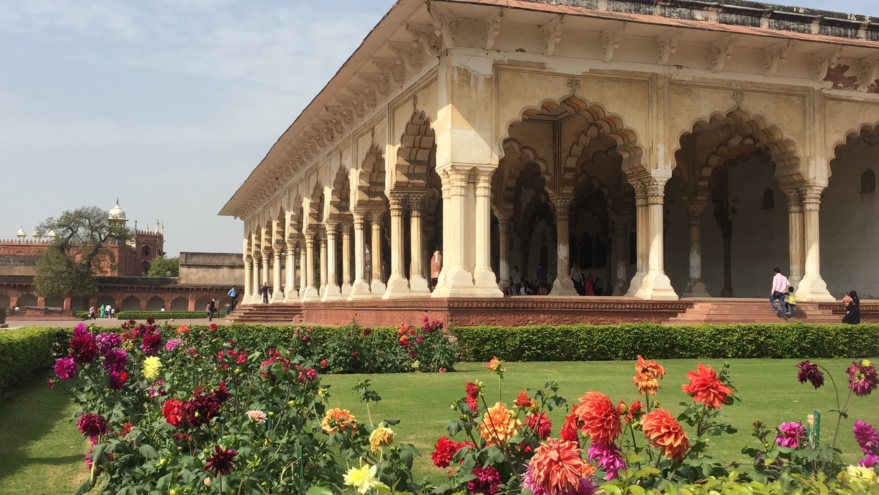Palais historique avec des arches et un jardin de fleurs.