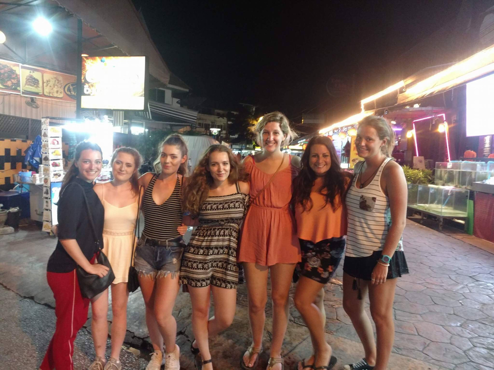 Group of friends posing in a vibrant street market at night.