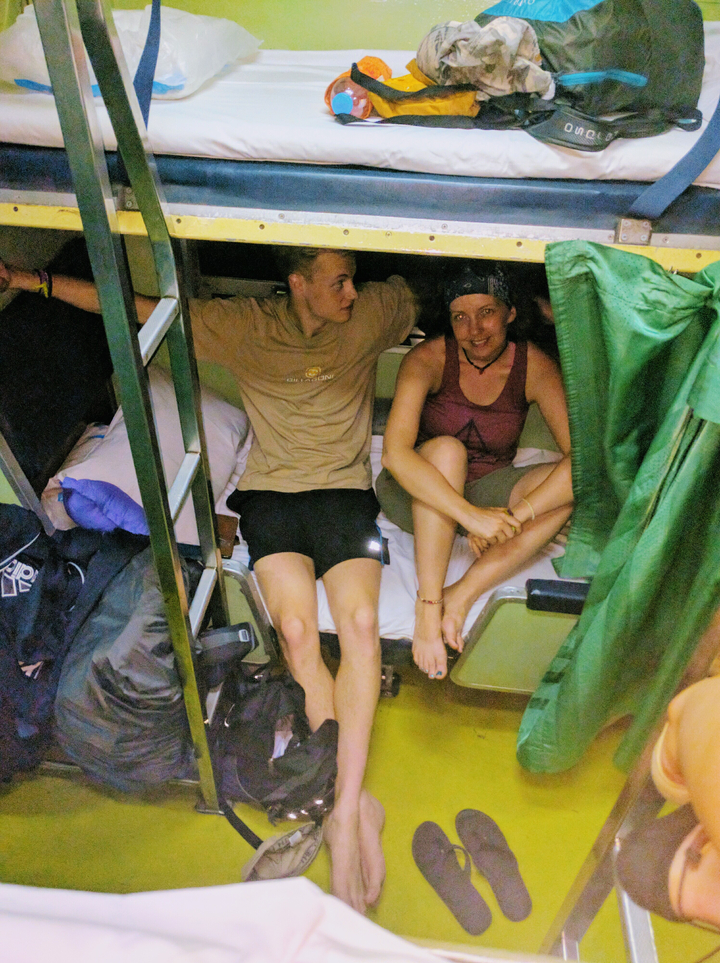 Two people sitting in a small cabin with bunk beds.