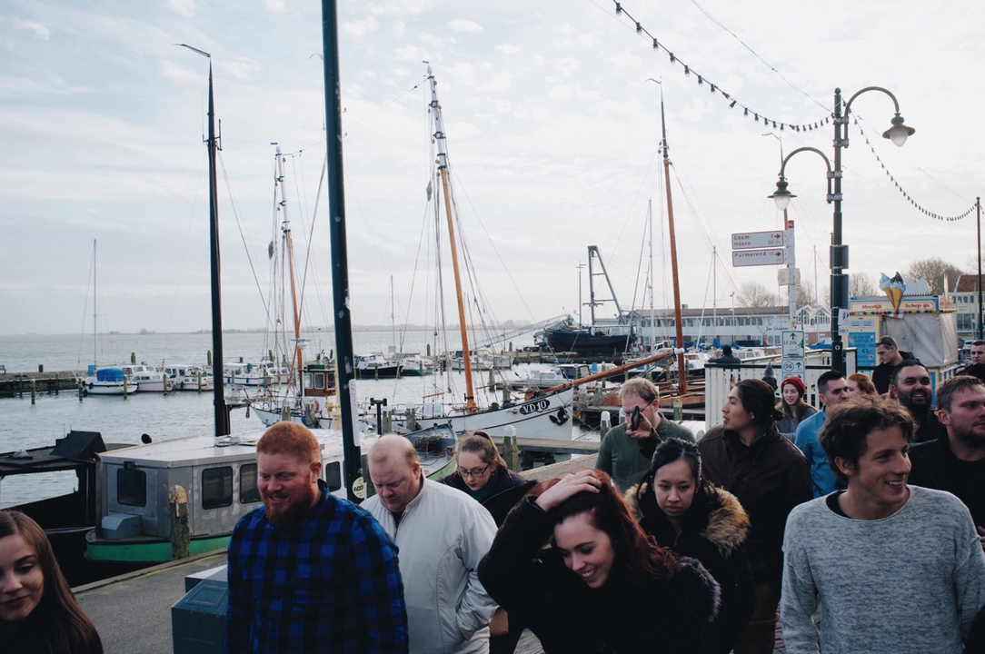 Foule de personnes marchant près des quais avec des voiliers.