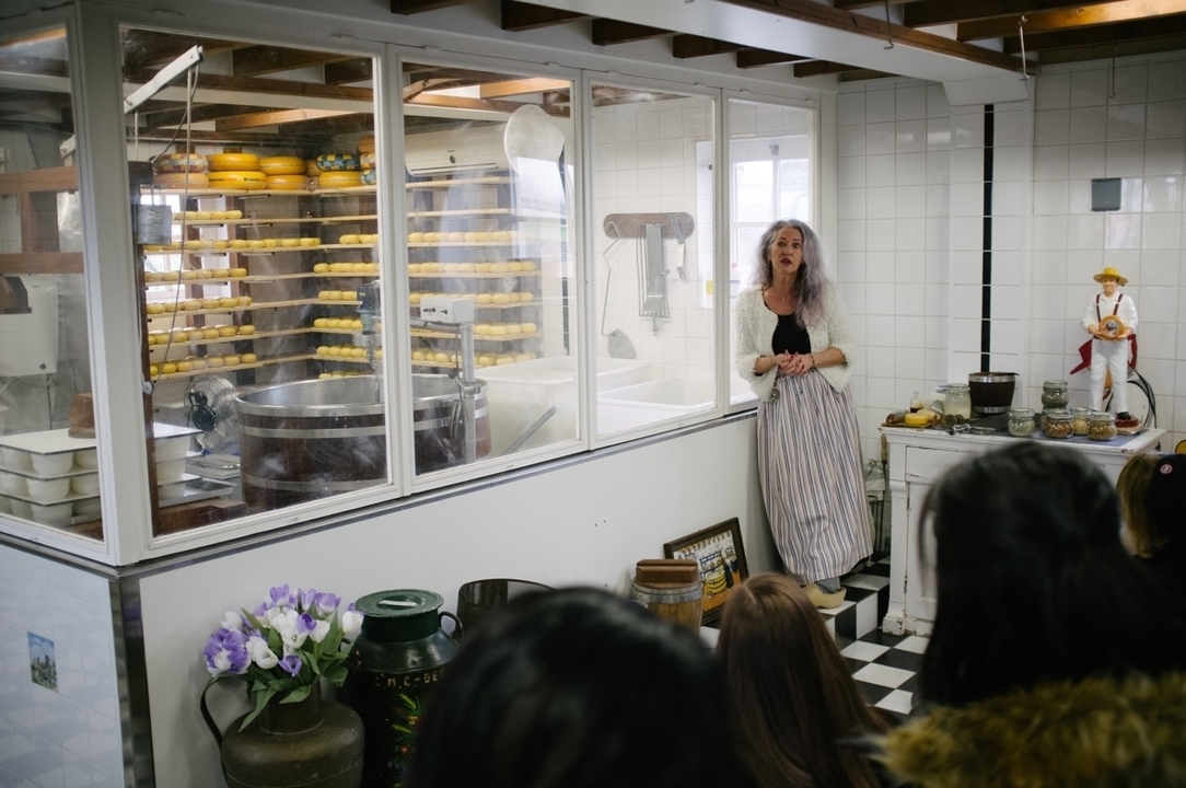 Personne expliquant le processus de fabrication du fromage dans un établissement.