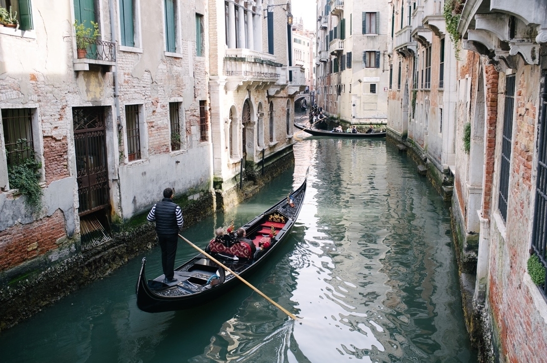 Une gondole navigue dans un canal étroit avec des bâtiments historiques.