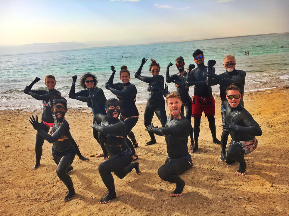 Groupe de personnes couvertes de boue posant sur une plage.