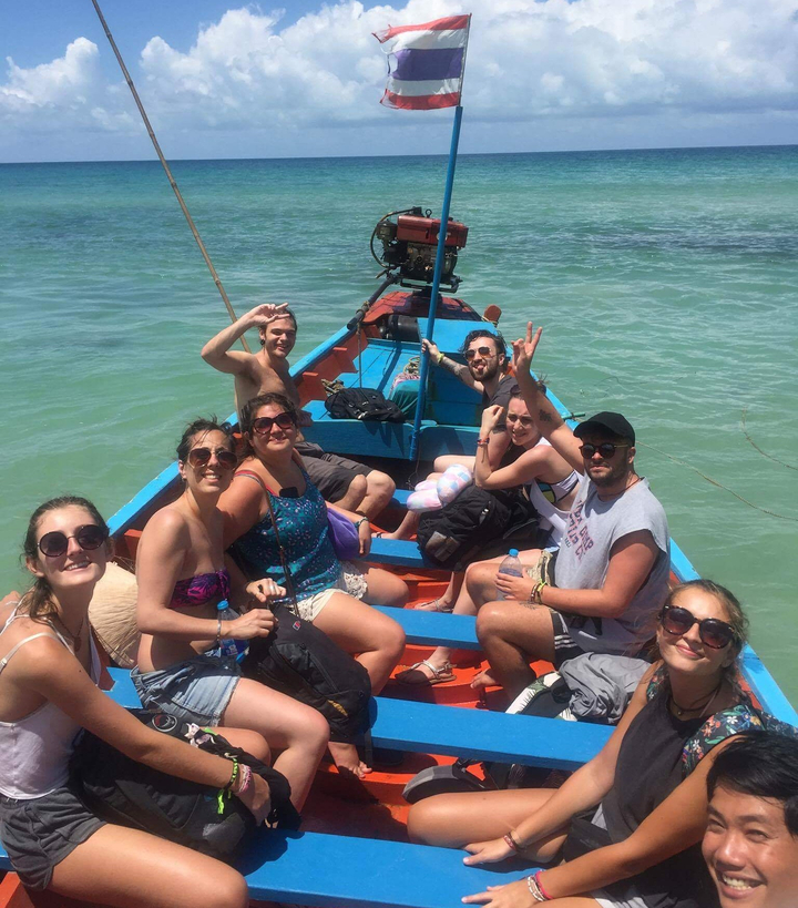 Group of people on a vibrant traditional boat in clear waters.