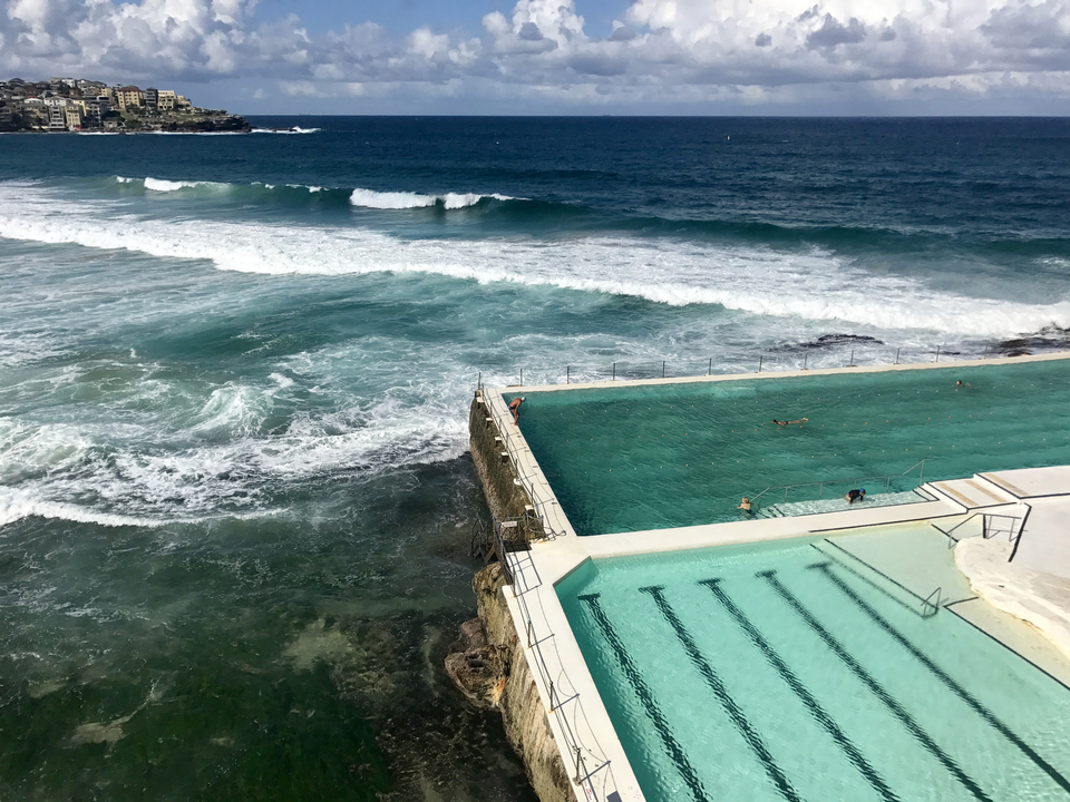 Ocean pool beside crashing waves on a rugged coastline.