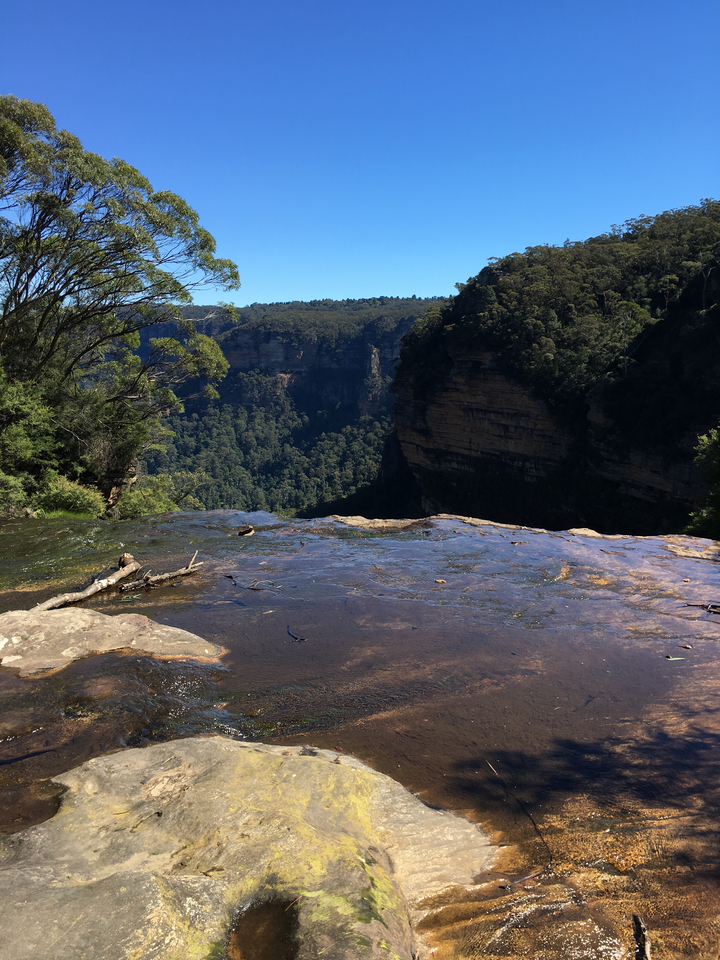 View from top of a waterfall with valley in the background.