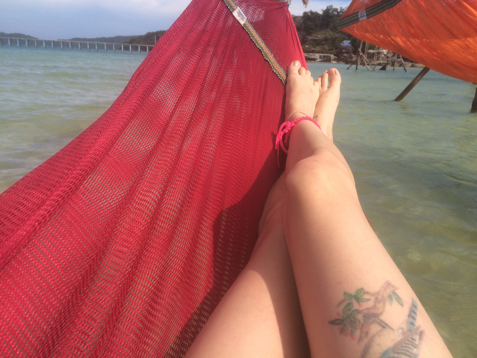 Person relaxing in a hammock with a view of the water.
