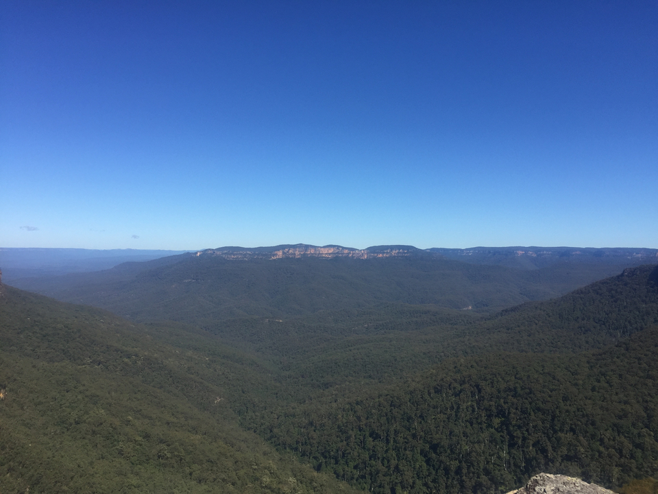 Expansive view of a mountainous landscape under a clear blue sky.