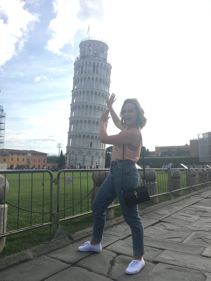 Personne posant avec humour devant la tour penchée de Pise.