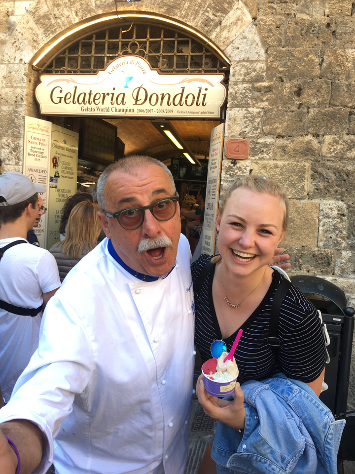Des gens heureux posant avec un chef à l'extérieur d'un restaurant.