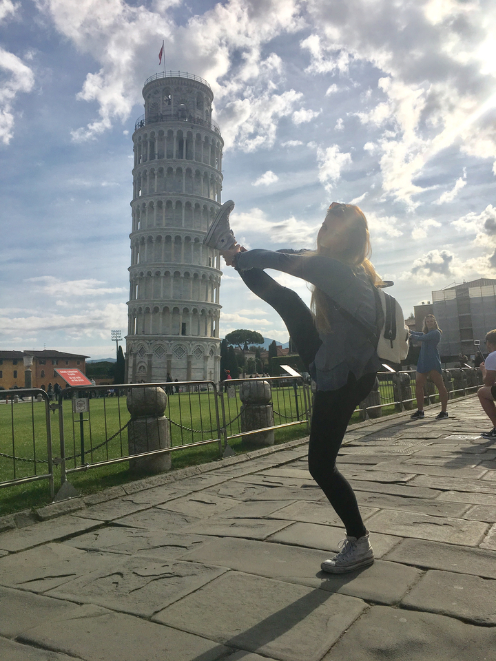 Personne faisant un numéro d'équilibriste devant la tour penchée de Pise.