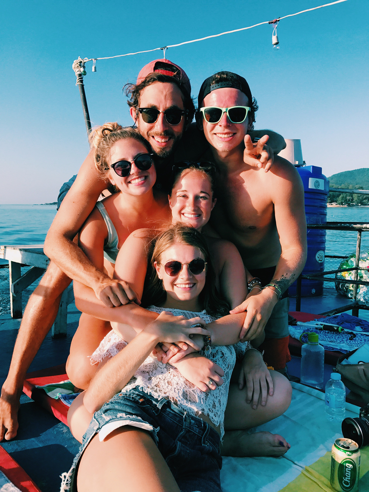 Group of friends hugging on a boat with ocean background.