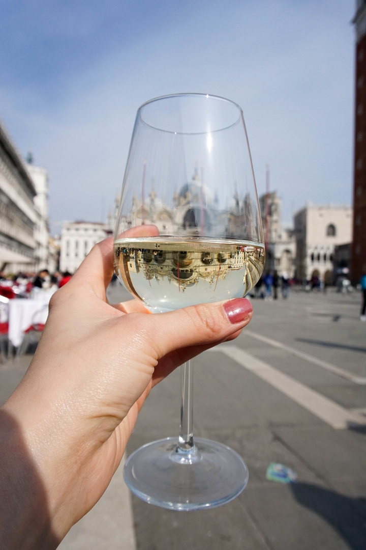 A glass of wine with the reflection of St. Mark's Basilica in Venice.