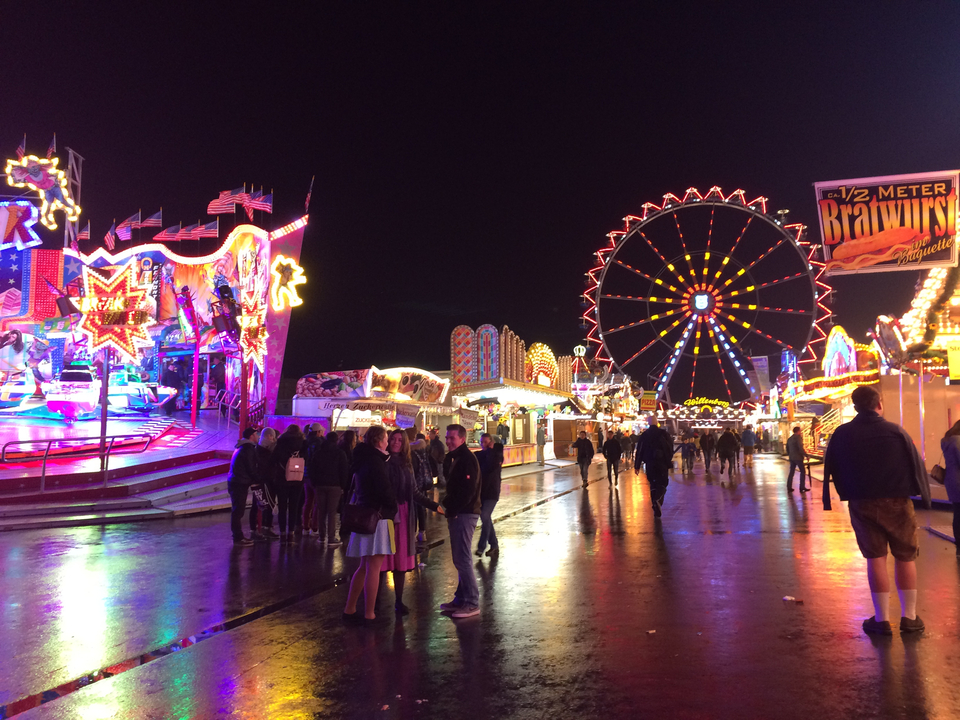 Fête foraine nocturne avec des lumières vives et une grande roue.