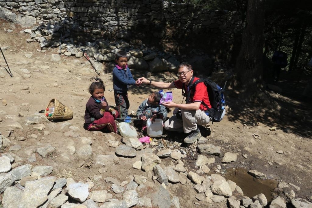 Person distributing items to local children in a rural setting.