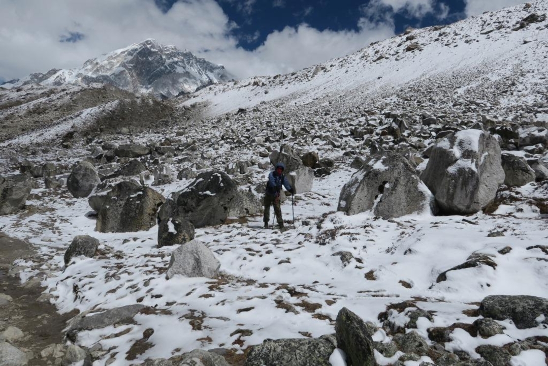 Trekkers in a rocky, snow-covered mountain landscape.