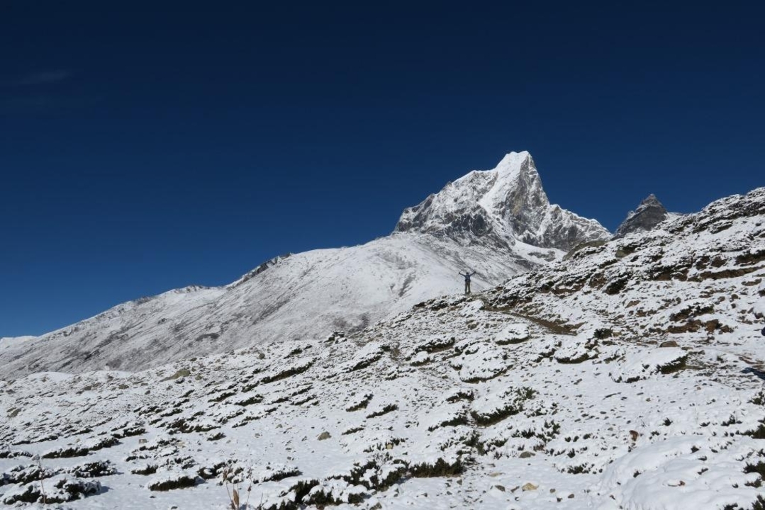 Snow-covered mountain landscape with a lone figure and distant peaks.