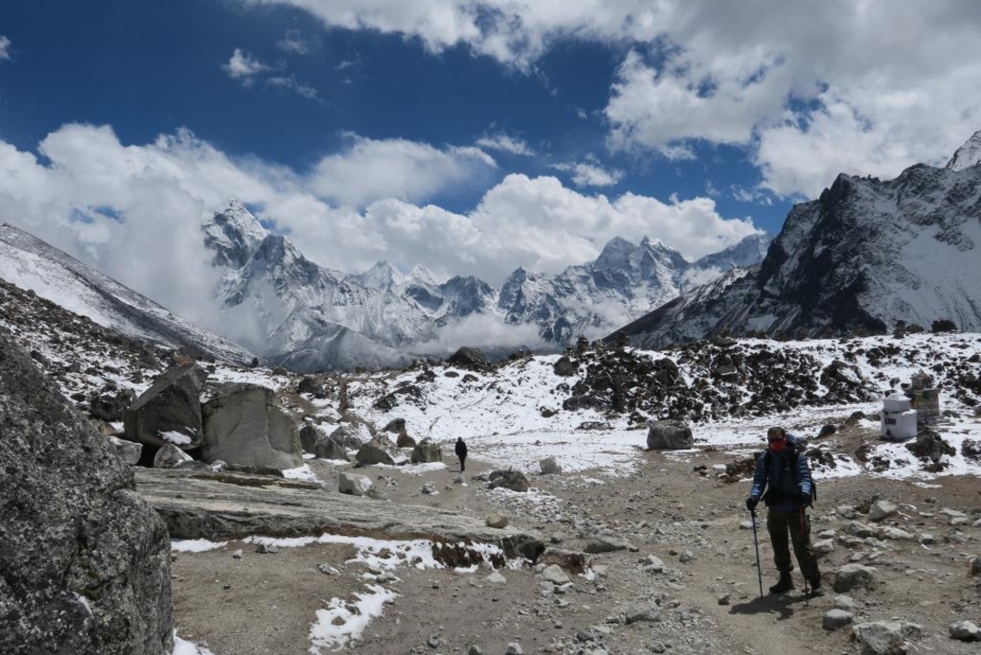 Trekkers on a trail with snowy mountains in the background.