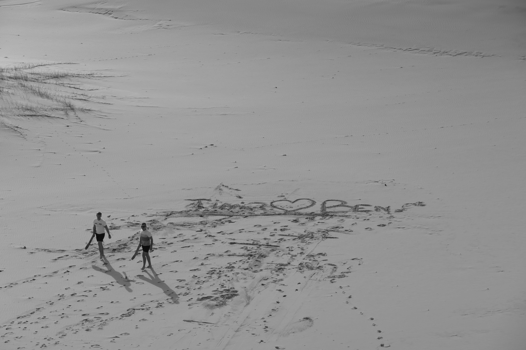 Deux personnes marchant sur le sable et écrivant dans le sable.