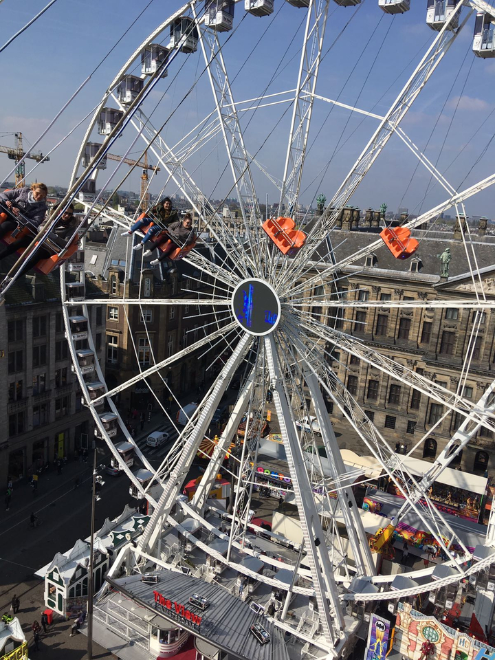 Grande roue avec des personnes en train de monter au-dessus d'une place de la ville.