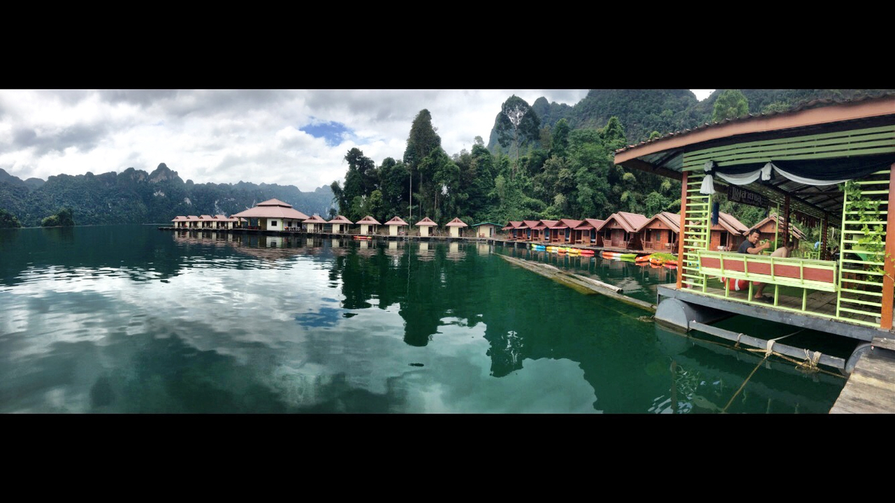 Floating bungalows on a serene lake surrounded by forested hills.
