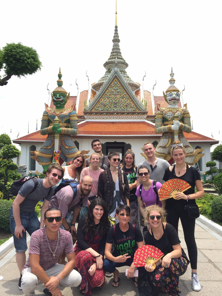 Group of people posing in front of a temple with guardian statues.