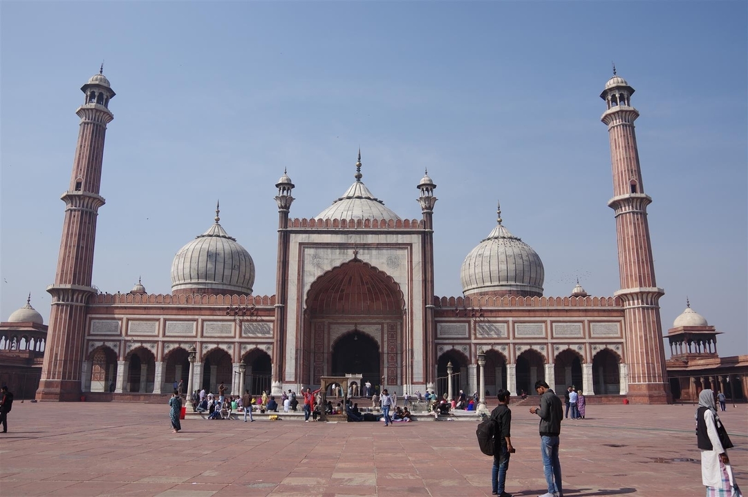 Grande mosquée avec minarets et personnes dans la cour.