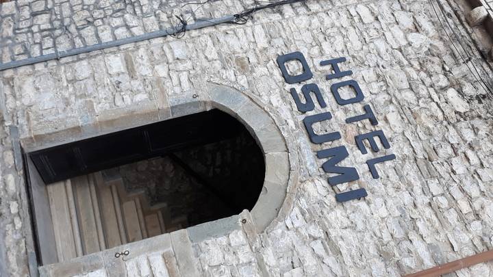 Entrée avec murs de pierre et panneau métallique au-dessus, incliné.