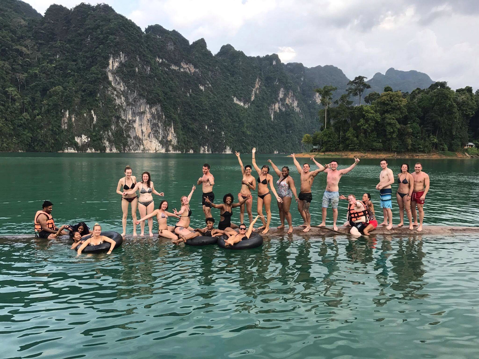 Large group having fun on a floating log in a lake.
